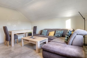 A living room with a sofa, a coffee table, a dining table, and chairs.