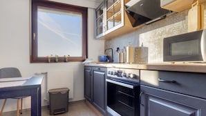Una cocina compacta con ventana, armarios, un microondas y una estufa.
