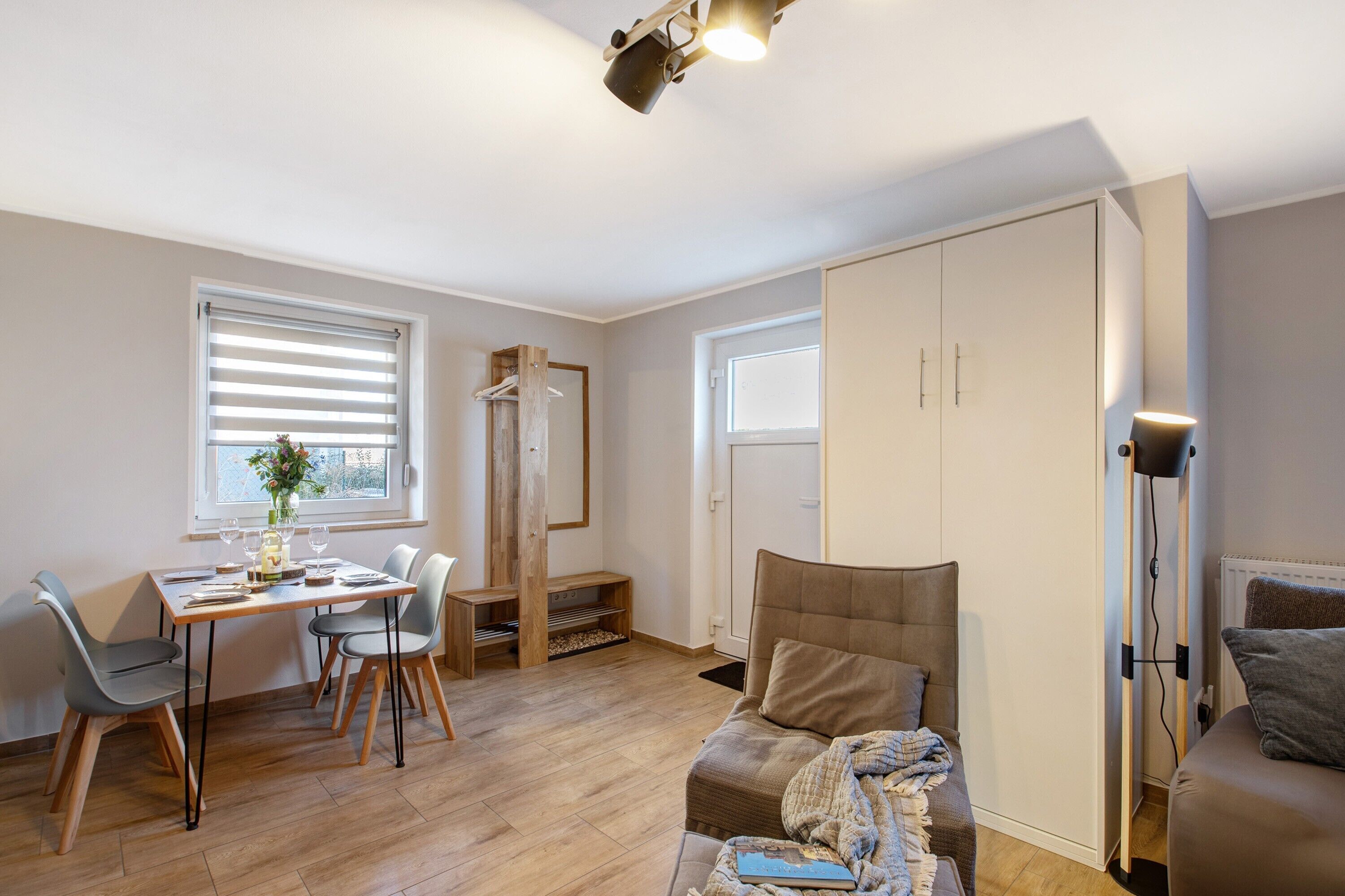 A modern apartment with a dining area, a sofa, a floor lamp, and a wardrobe.