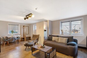 A modern living room with a sofa, dining table, chairs, and a coffee table.