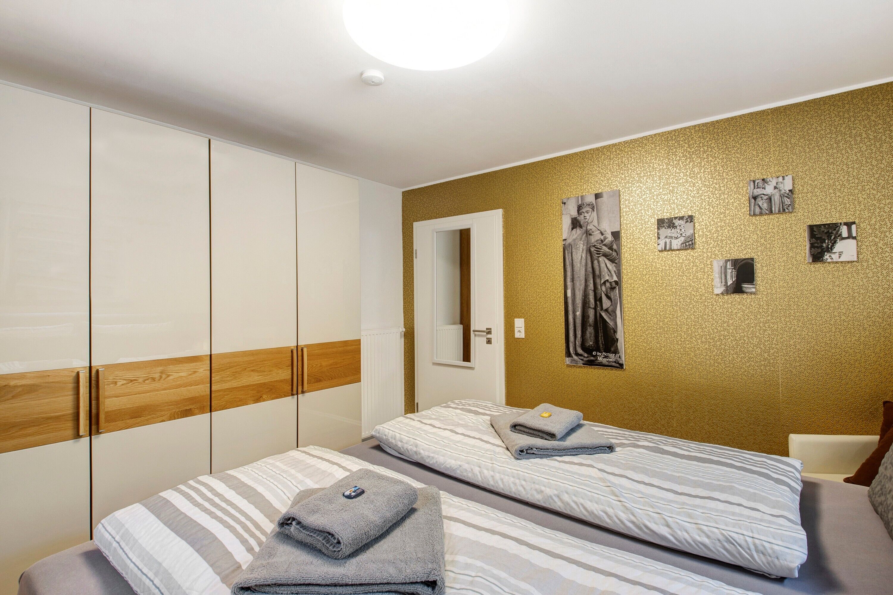 Een hotelkamer met twee bedden, een kast, een spiegel en een muur met afbeeldingen.