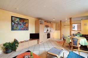 A kitchen with a dining area, a television, and a painting on the wall.