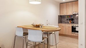 A modern kitchen with wooden cabinets, a round dining table, and two white chairs. - Vacation apartment '2' with Wi-Fi (Meersburg)