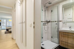 Une salle de bain moderne avec une douche à parois de verre, un meuble-lavabo en bois et un grand miroir.