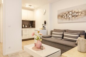 A modern living room with a sofa, coffee table, and a kitchen area in the background.