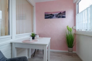Une pièce avec une table blanche, un mur rose et une fenêtre donnant sur un pont.