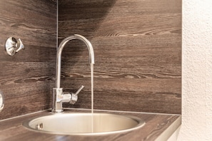 Une salle de bain avec un mur en bois, un évier en acier inoxydable et un robinet moderne.