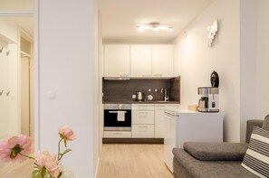 A modern kitchen with white cabinets, a built-in oven, and a coffee machine.