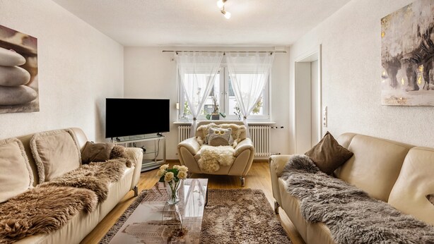 A living room with a sofa, armchair, and a flat-screen TV. - Quiet, Modern Apartment with Garden near Lake Steißlingen and Lake Constance (Steißlingen)
