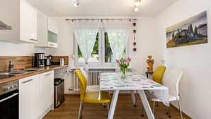 A modern kitchen with white cabinets, a wooden countertop, and a dining area with a table and chairs. - Quiet, Modern Apartment with Garden near Lake Steißlingen and Lake Constance (Steißlingen)