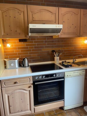 Una cocina con armarios de madera, un tostador, una tetera, un horno y un lavavajillas.