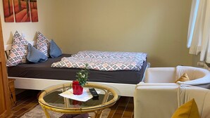 Una habitación acogedora con una cama, una mesita redonda pequeña, una silla y un sofá.