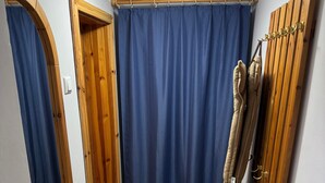 Un pasillo estrecho con paredes de madera, una cortina azul y un perchero de madera.