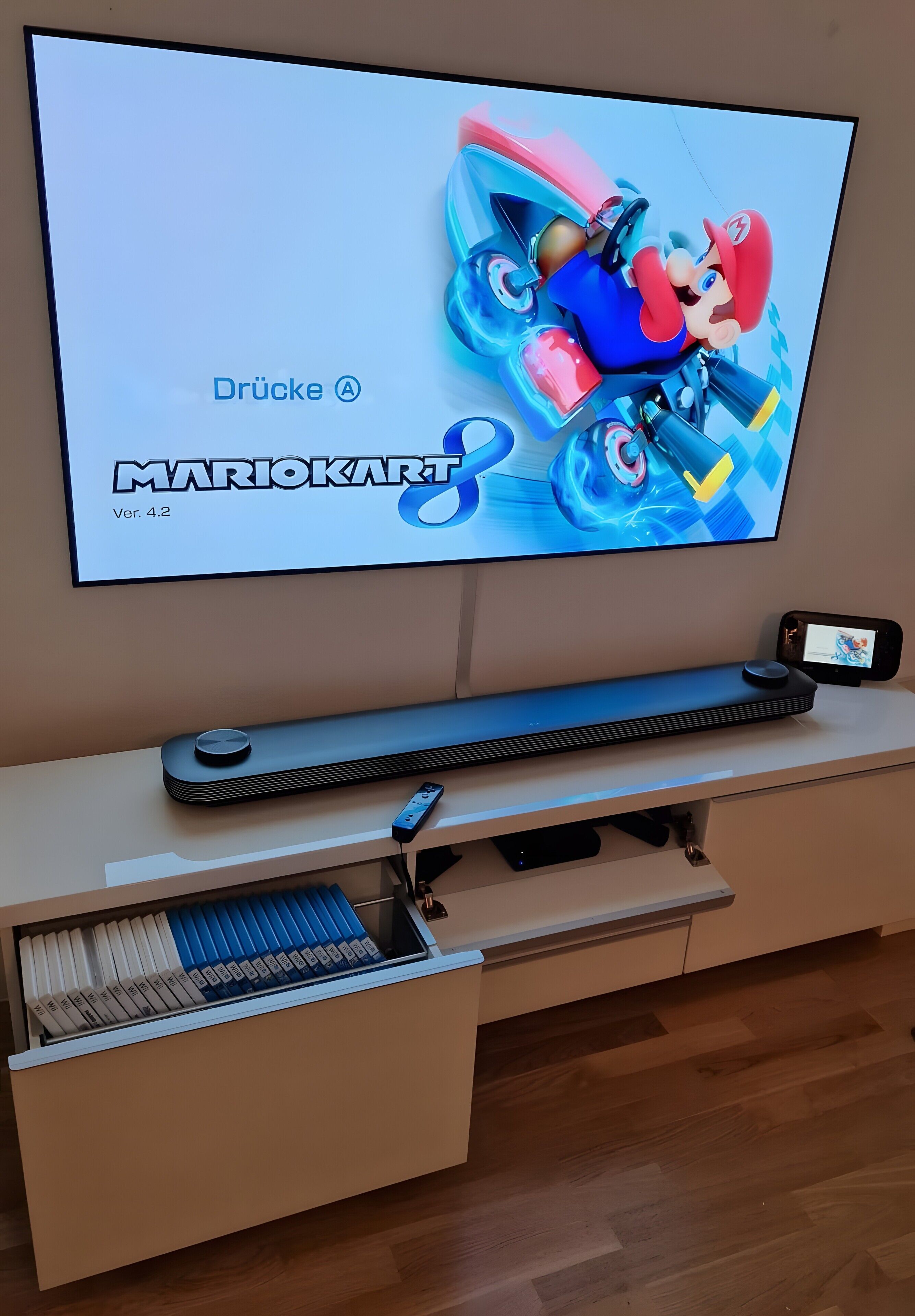 Een televisie waarop Mario Kart wordt gespeeld, een toetsenbord en een smartphone op een standaard.