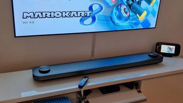Een televisie waarop Mario Kart wordt gespeeld, een toetsenbord en een smartphone op een standaard.