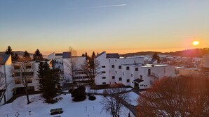 Et boligområde med moderne hvide bygninger, klar himmel og solnedgang i baggrunden.