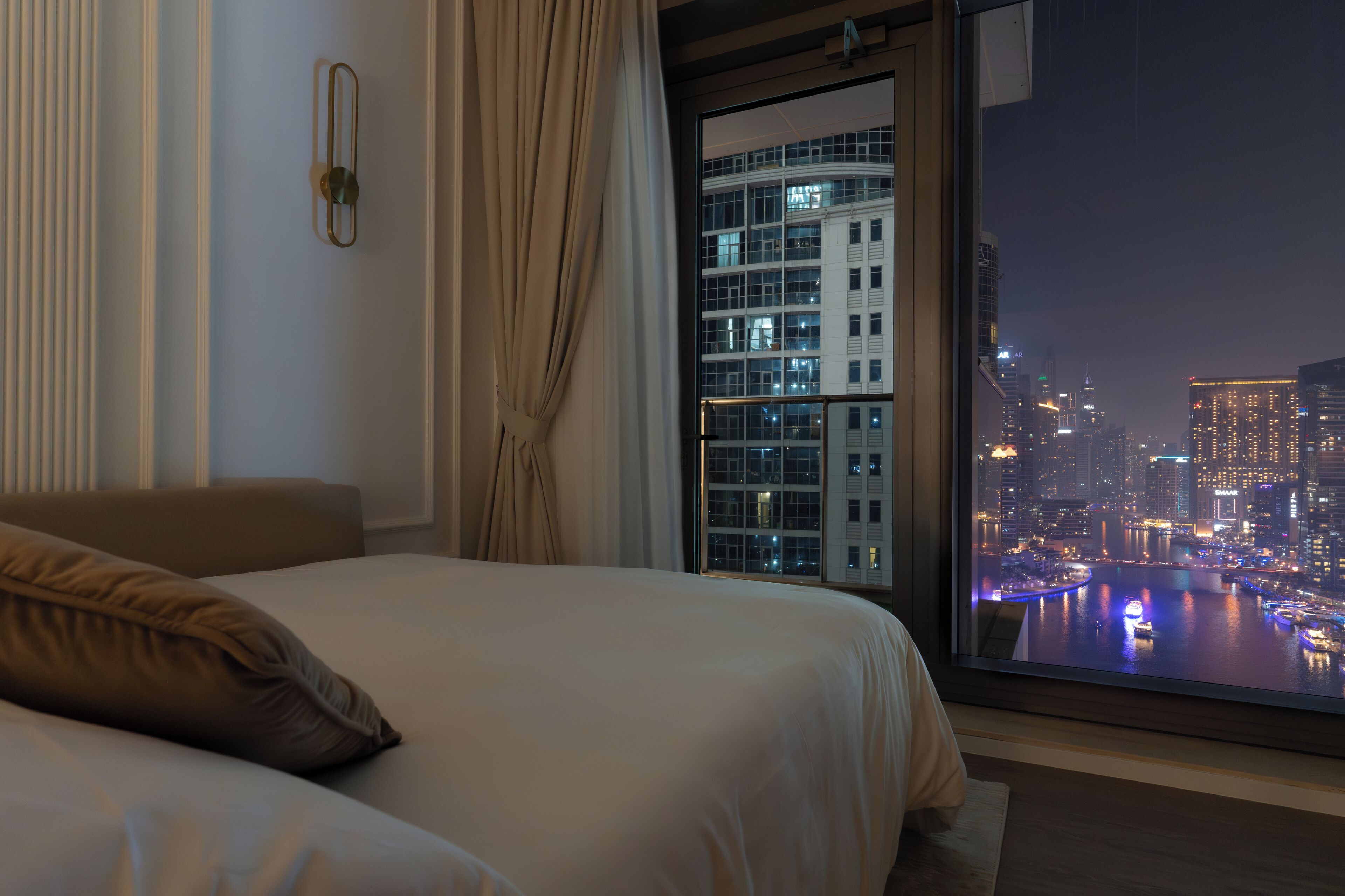 Une chambre d’hôtel dotée d’une grande fenêtre donnant sur la ville, avec une vue imprenable de nuit.