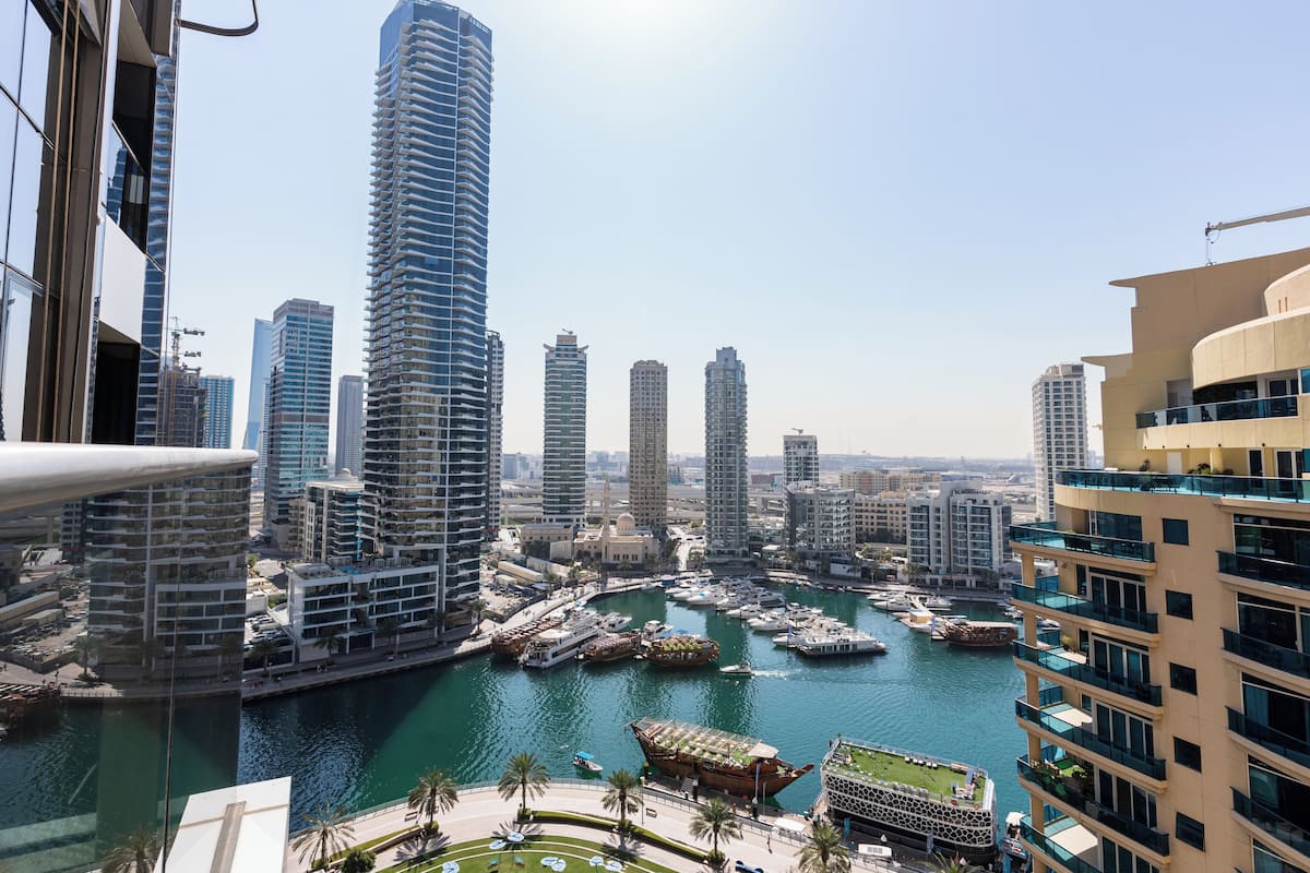 A marina with boats, surrounded by high-rise buildings and a clear sky.