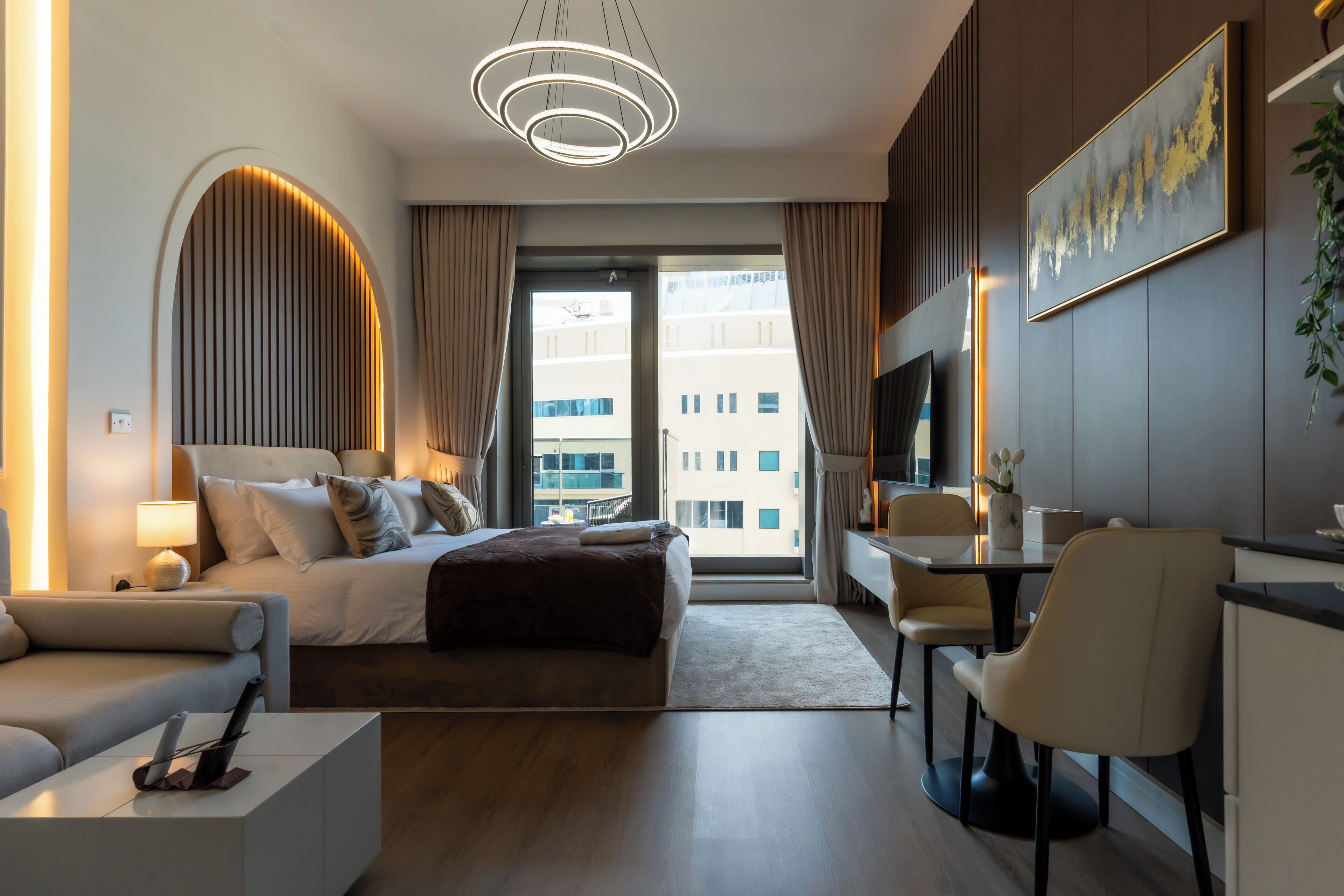 A modern hotel room with a large bed, a desk, and a TV.