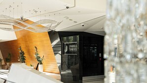 A modern lobby with a reception desk, a wooden accent wall, and a sign for 'Sparkle Towers at Dubai Marina'. - Dubaiashome - Luxury Special Stay (Dubai)