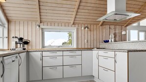 Eine moderne Küche mit weißen Schränken, einer Granitarbeitsplatte und einer Holzbalkendecke.