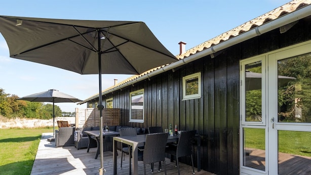 Een terras met buitenmeubilair, waaronder tafels en stoelen, en een grote parasol.