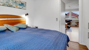 Een slaapkamer met een groot bed, een houten hoofdeinde, een wandlamp en een plafondlamp.