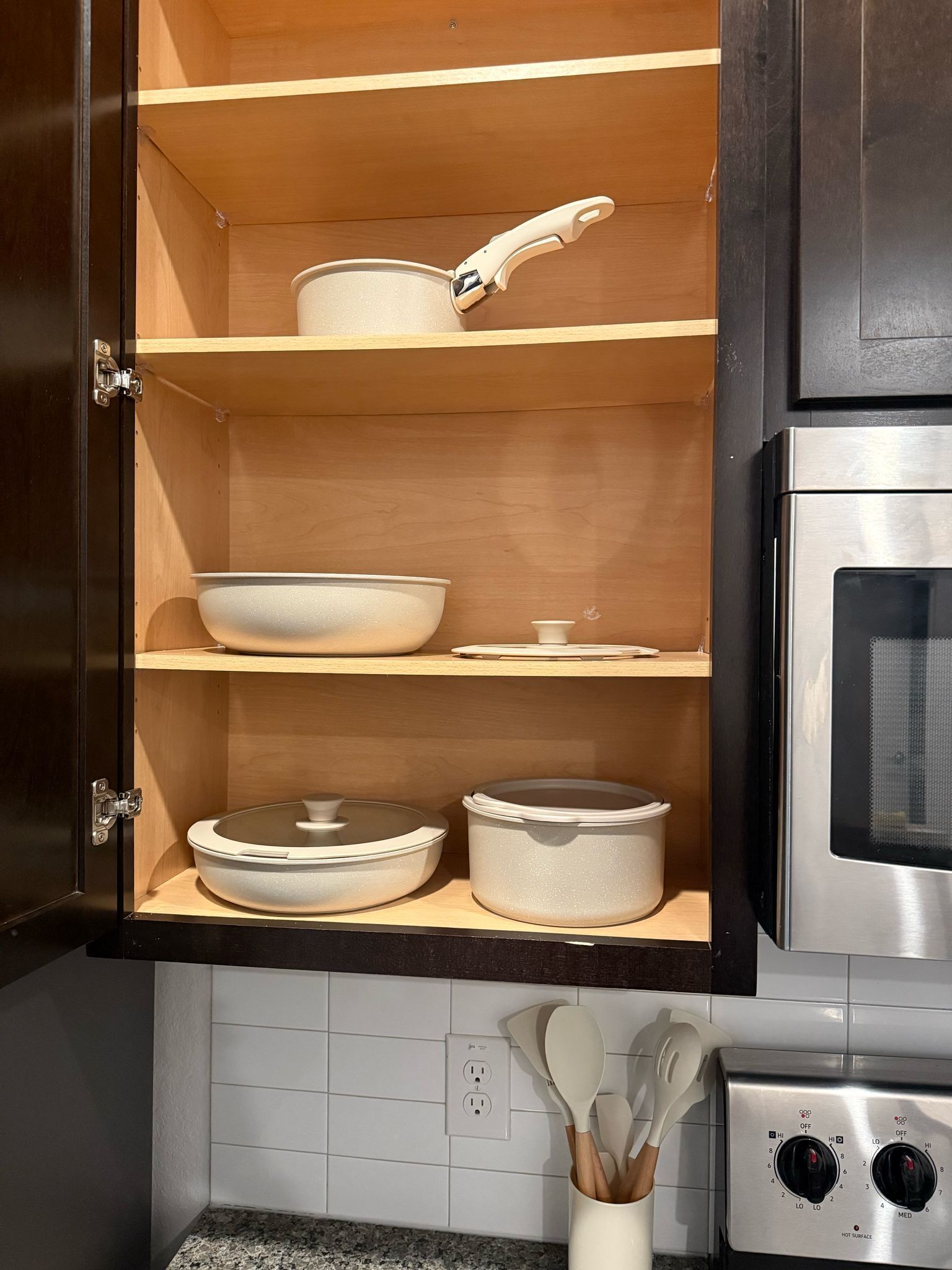 A kitchen with wooden shelves, a stainless steel oven, and a white countertop with a knife block.