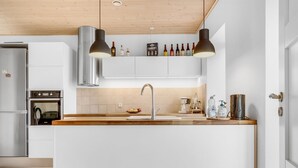 Cuina moderna amb una illa central, electrodomèstics d'acer inoxidable i sostre de fusta.