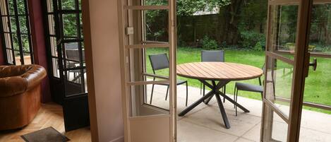 An open sliding glass door leading to a patio with a round wooden table and four chairs.