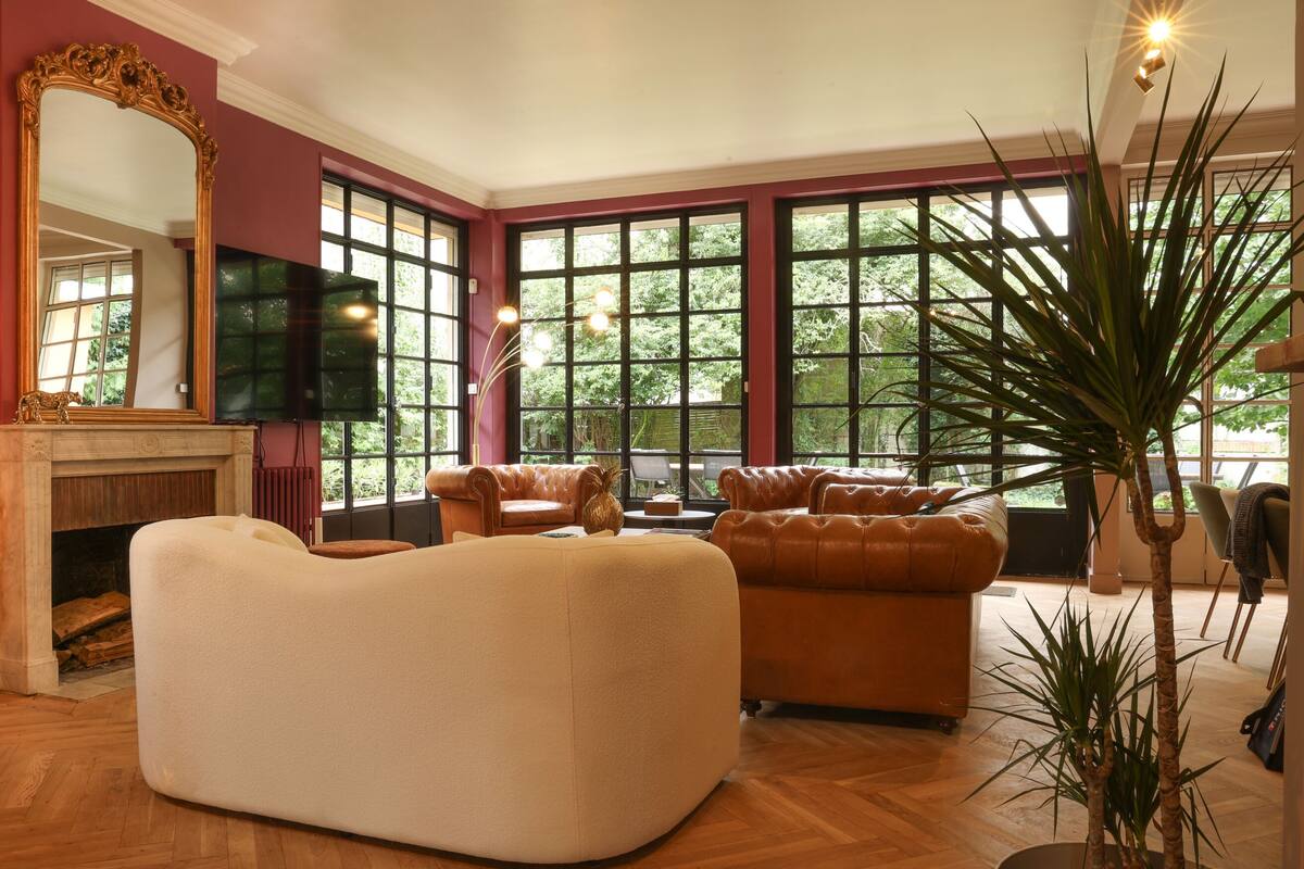 Een kamer met een open haard, leren banken, een grote spiegel en een televisie.