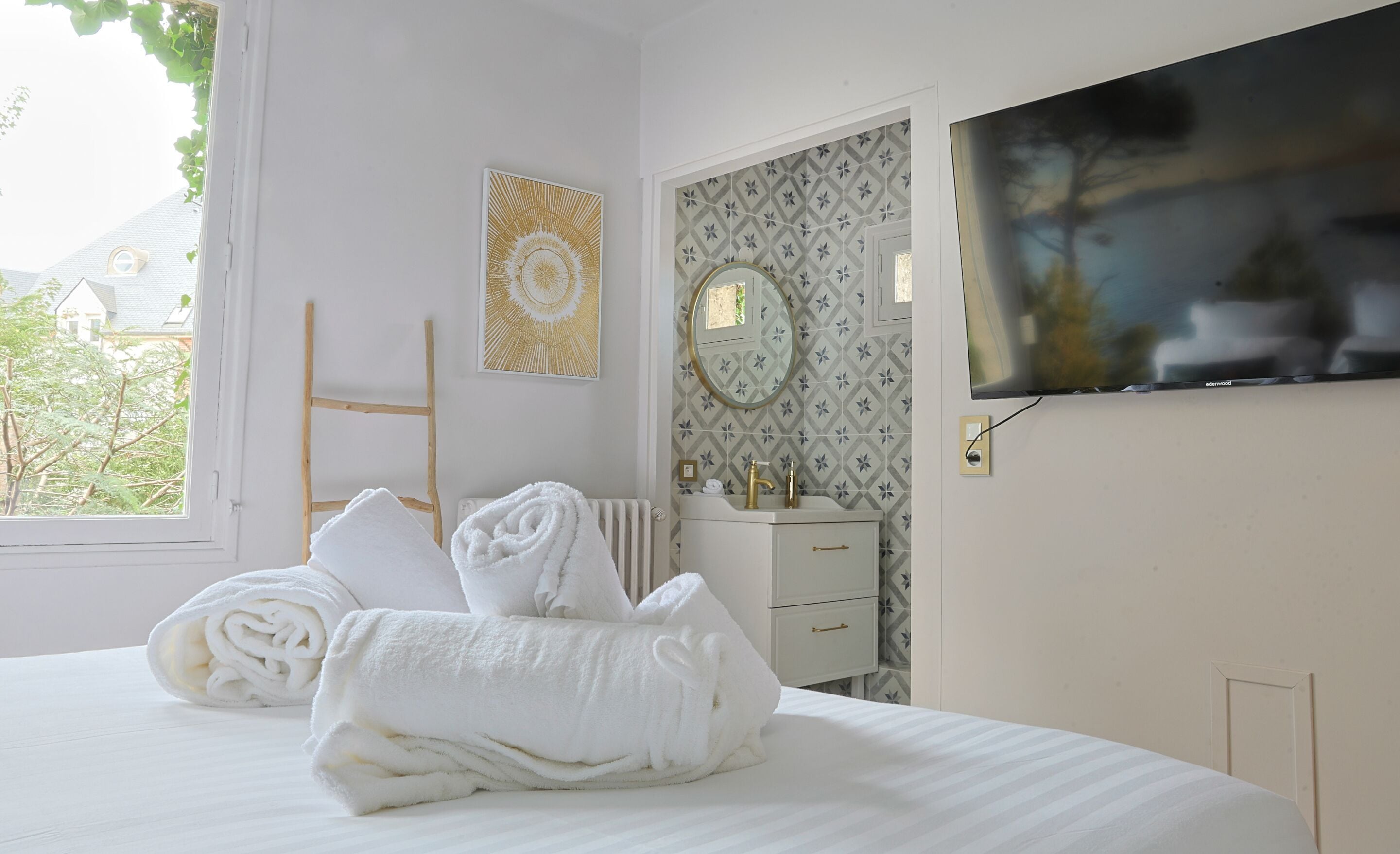 Ein Hotelzimmer mit Bett, Fernseher und einem Badezimmer mit Spiegel und Handtüchern.