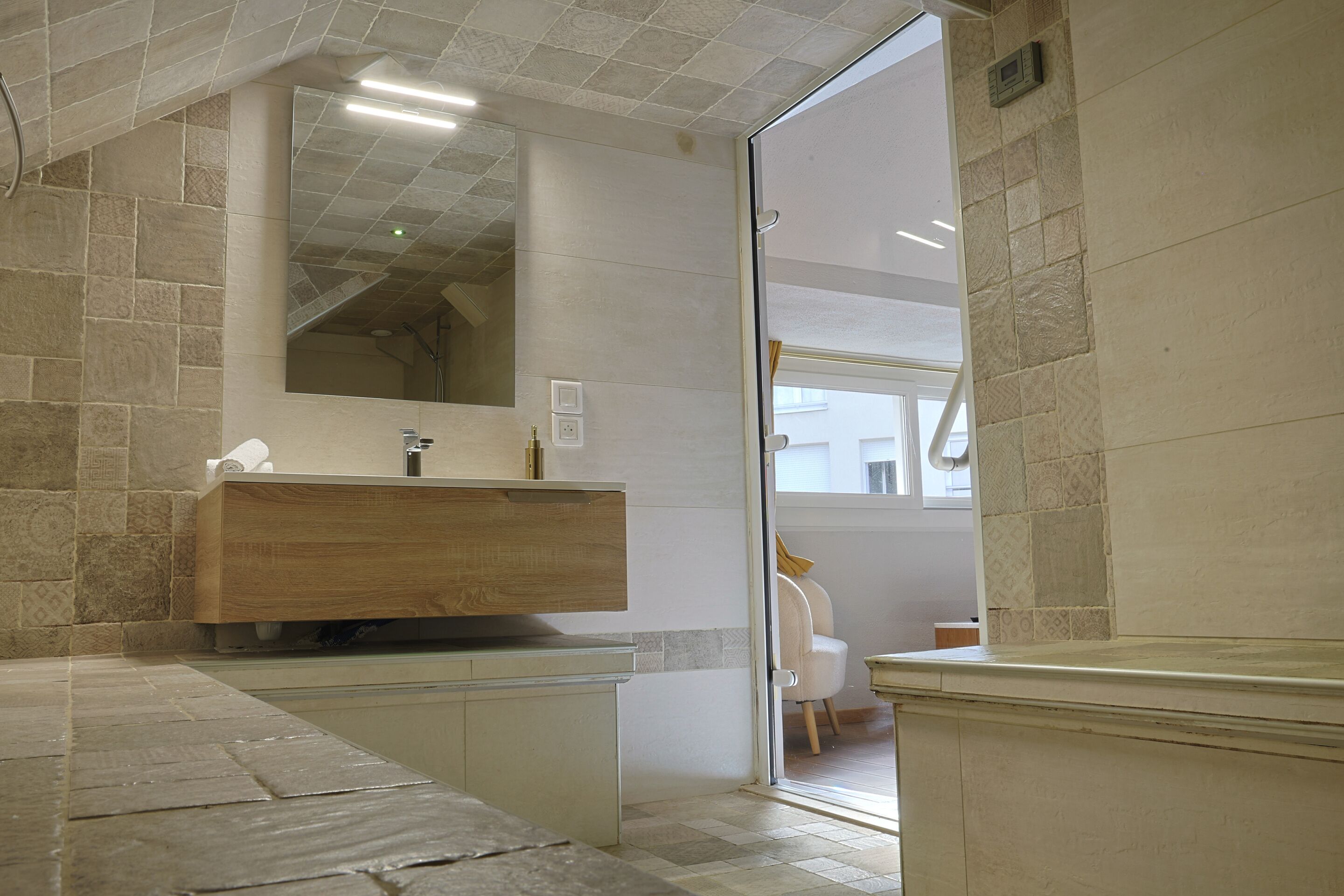 Une salle de bain moderne avec un meuble-lavabo en bois, un grand miroir et une porte de douche en verre.