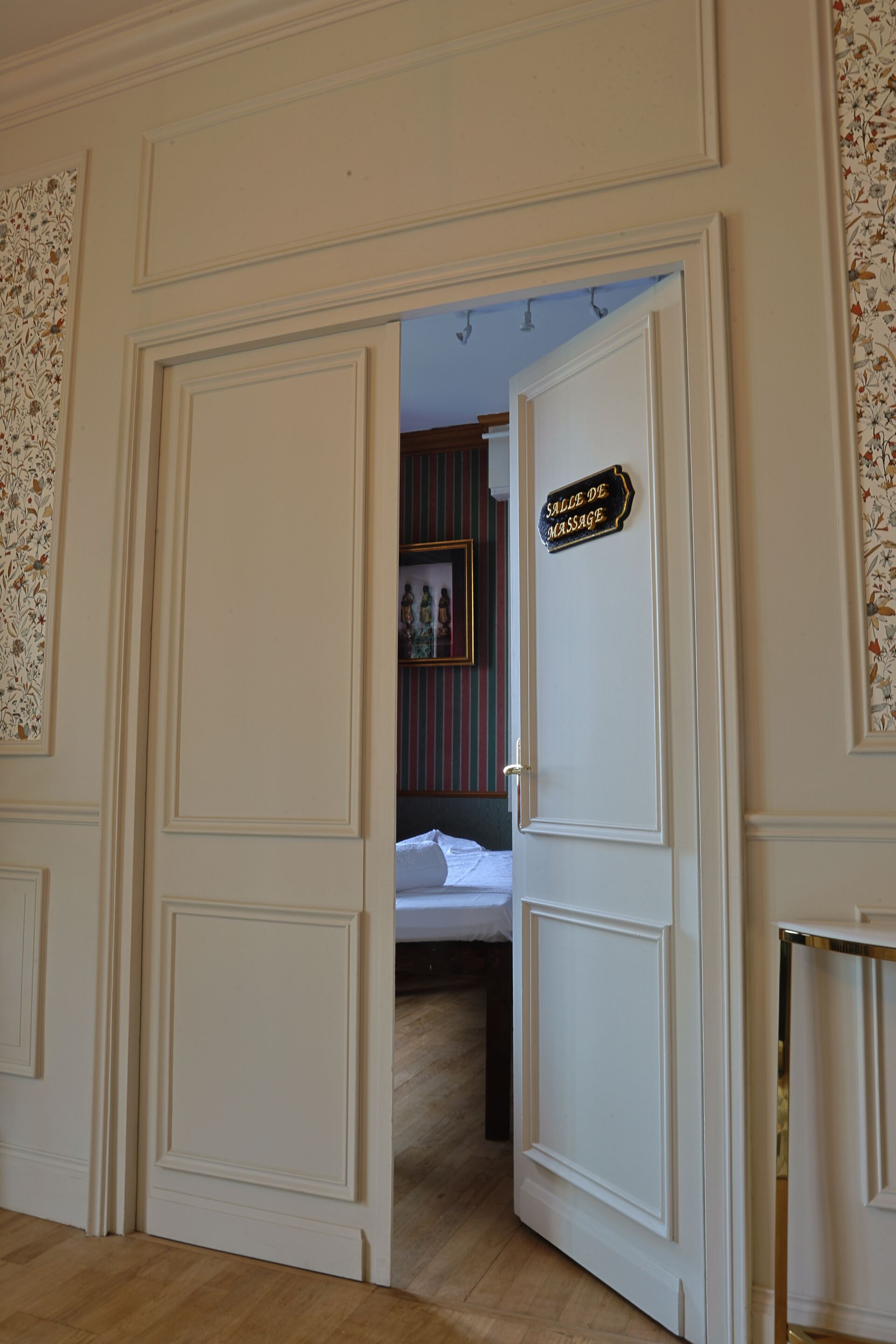 A room with a bed, a door with a sign, and a patterned wall.