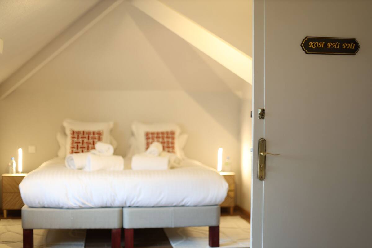 Een slaapkamer met een bed, twee nachtkastjes en een deur met een bordje.