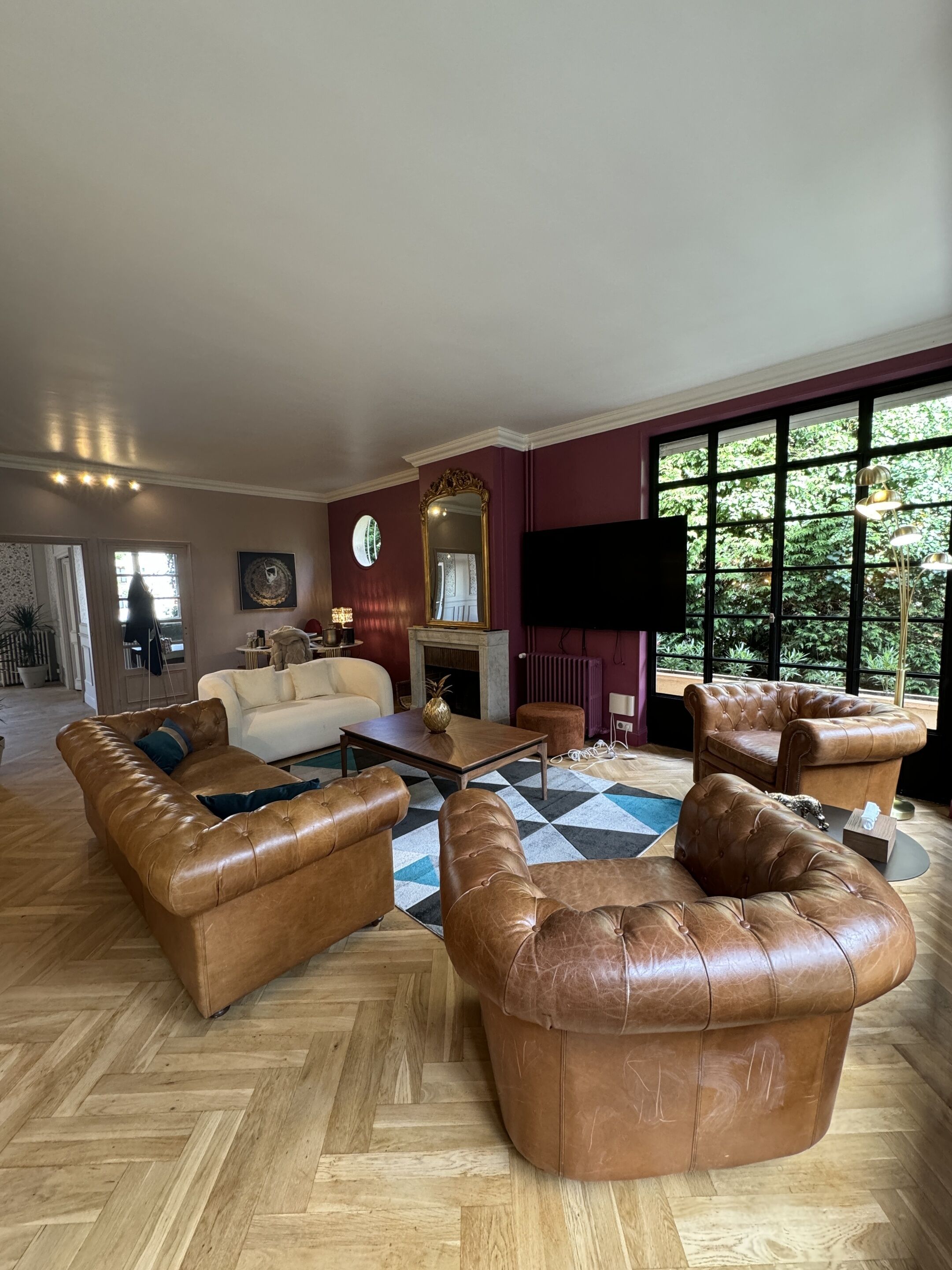 A spacious living room with leather sofas, a coffee table, and a fireplace.