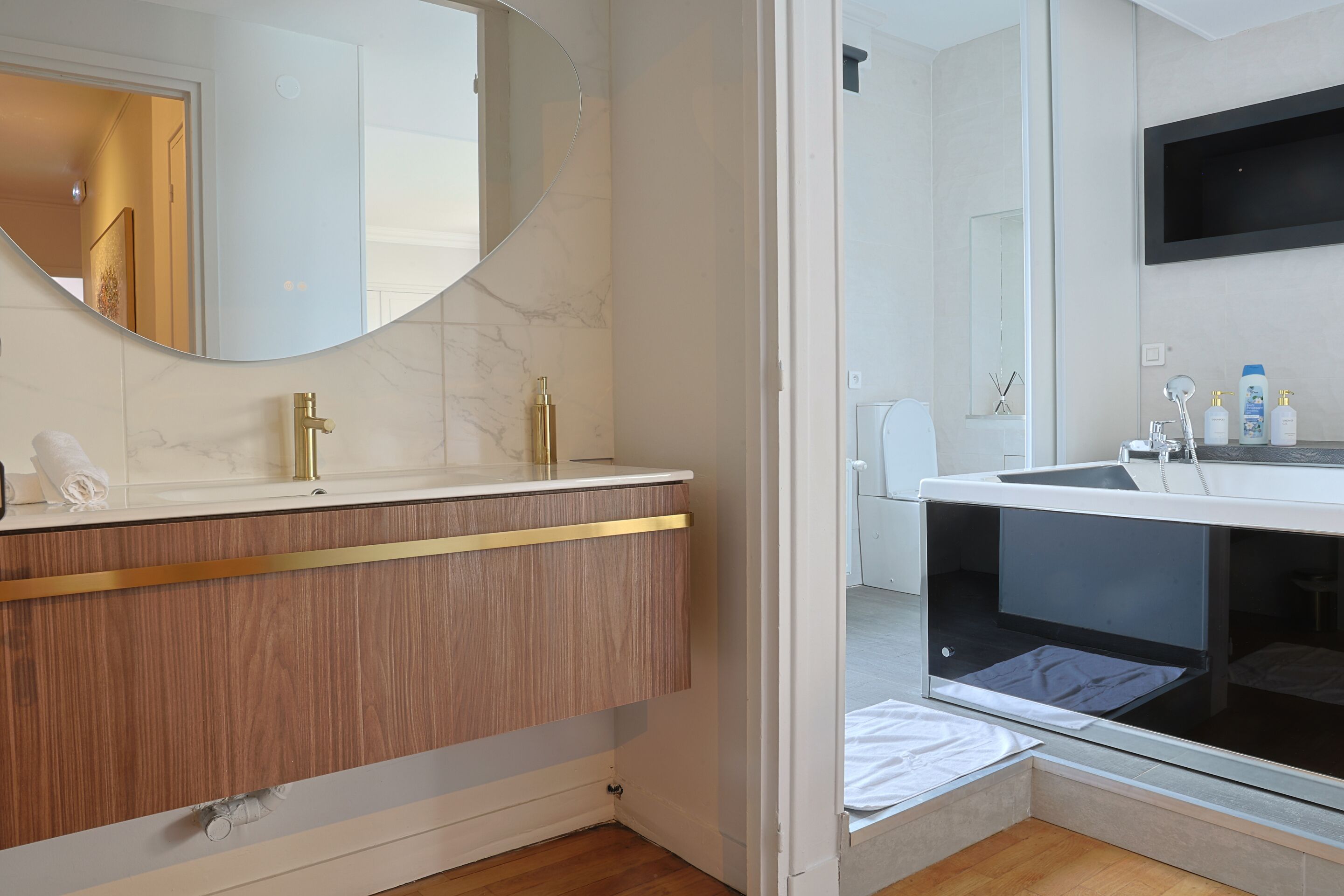 Une salle de bain moderne avec un meuble-lavabo en bois, un grand miroir et une douche intégrée.