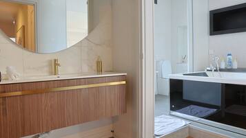 Un baño moderno con tocador de madera, un espejo grande y zona de ducha integrada.