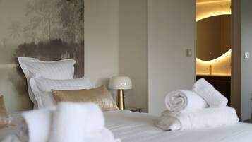A hotel room with a bed, pillows, a lamp, and a towel rack.
