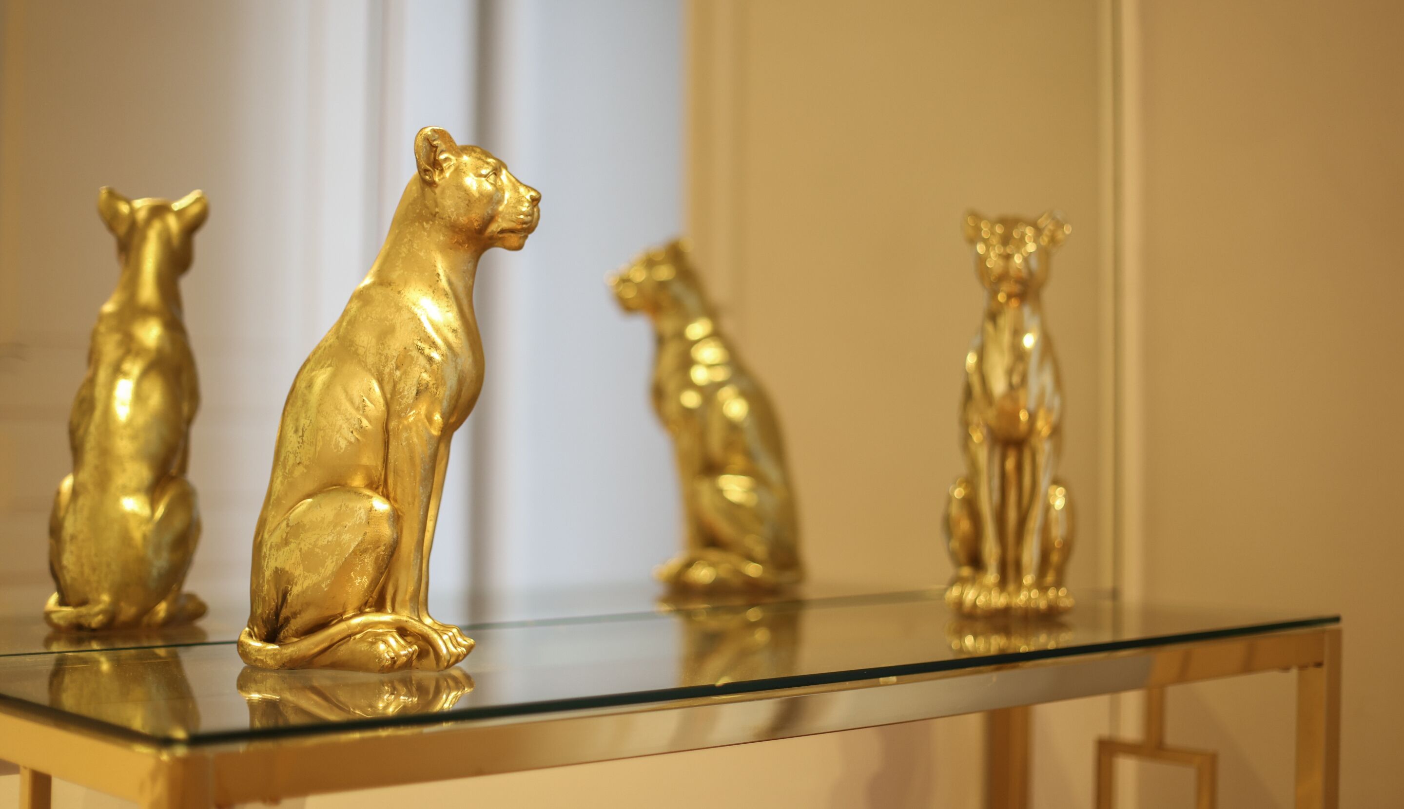 Una mesa de vidrio con tres figuritas doradas de animales.