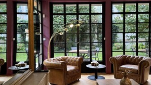 A room with large windows, a fireplace, a sofa, a coffee table, and a lamp.