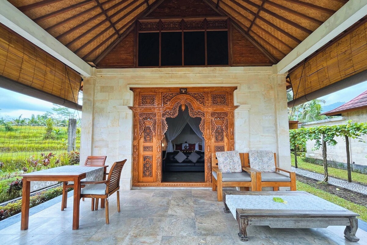 A covered outdoor seating area with a stone wall entrance leading to a bedroom.