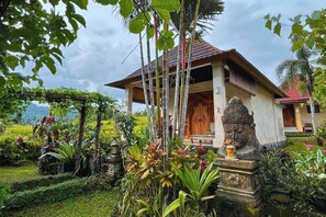 A traditional house with a tiled roof, surrounded by lush greenery and a well-maintained garden. - Villa Pastiny Santy Sidemen (Sidemen)