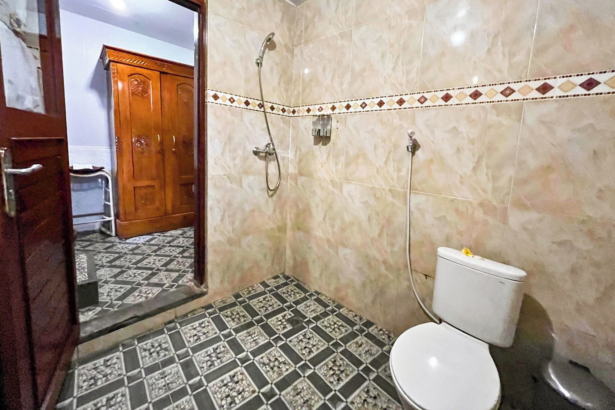 A bathroom with a toilet, shower, and tiled floor.