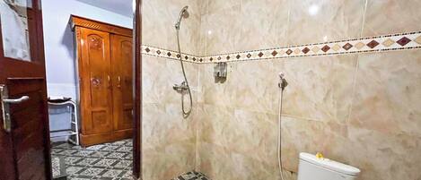 A bathroom with a toilet, shower, and tiled floor.
