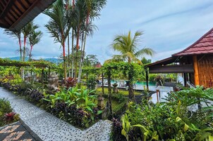 Un exuberante jardín con piscina, rodeado de plantas tropicales y una estructura de madera.