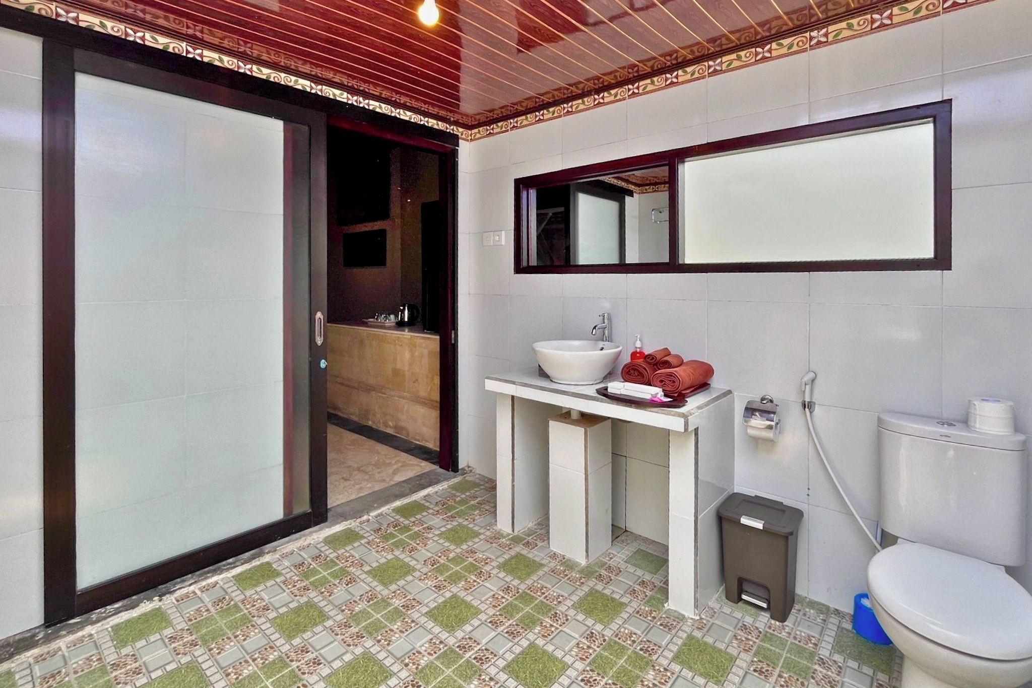 Une salle de bain avec un lavabo blanc, un miroir, des toilettes et une poubelle.