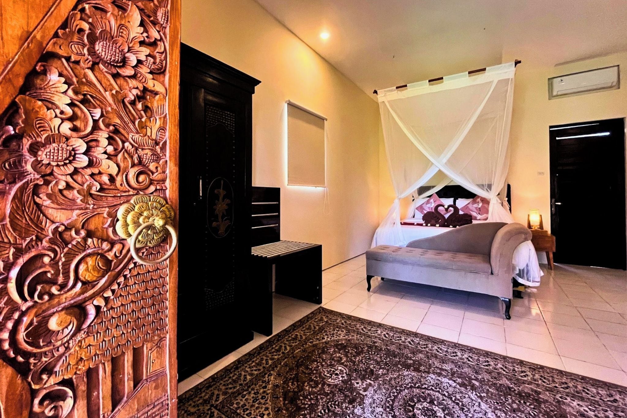 A bedroom with a bed under a canopy, a nightstand, a wardrobe, and a decorative wooden panel.