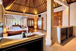 A hotel room with a bed, a bedside table with a kettle, and a large window.
