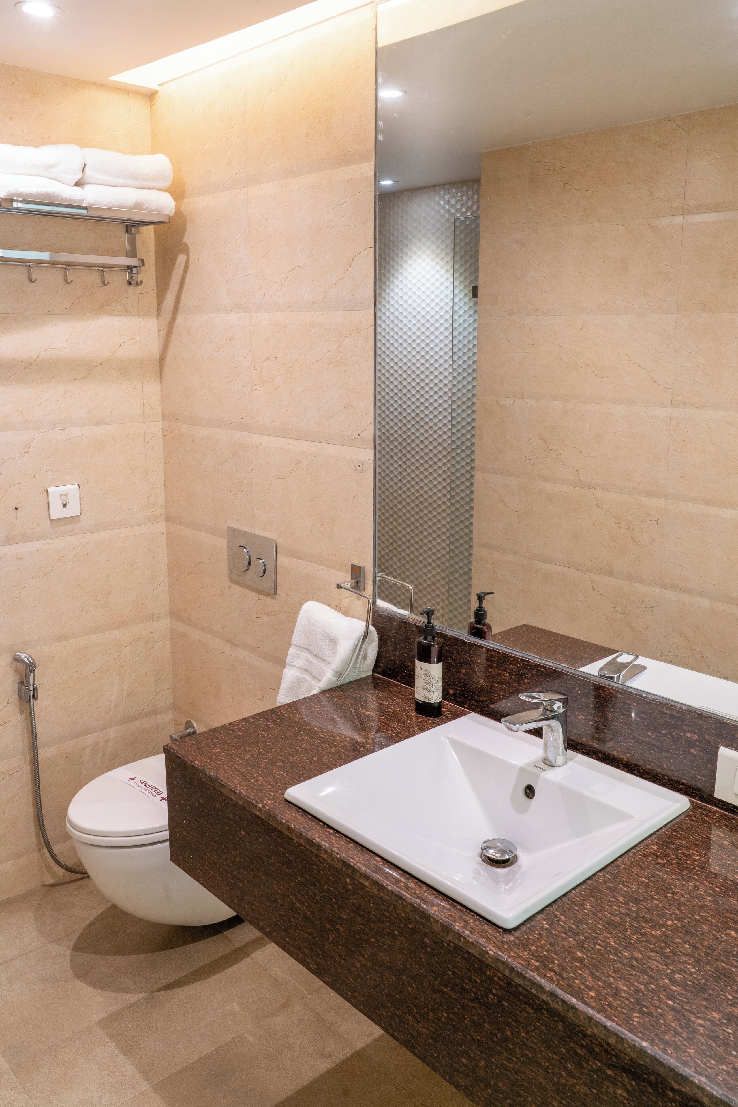 A bathroom with a white sink, a mirror, a towel rack, and a toilet.